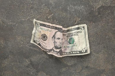 Photo of One crumpled dollar banknote on grey table, top view