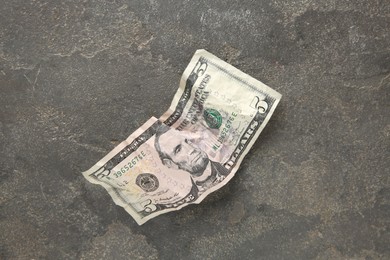 Photo of One crumpled dollar banknote on grey table, top view