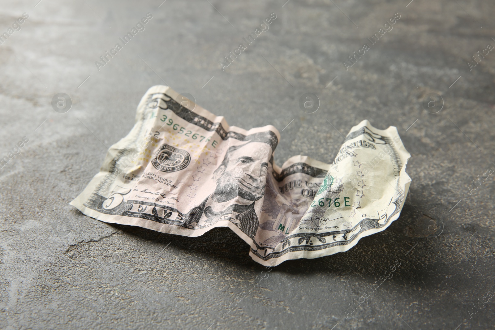 Photo of One crumpled dollar banknote on grey table, closeup