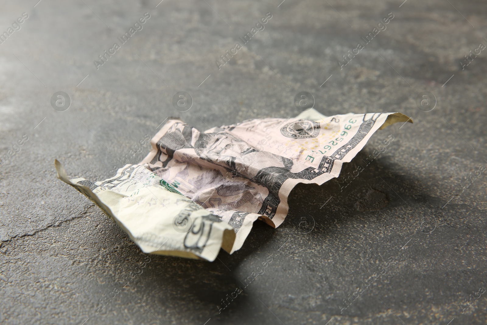 Photo of One crumpled dollar banknote on grey table, closeup