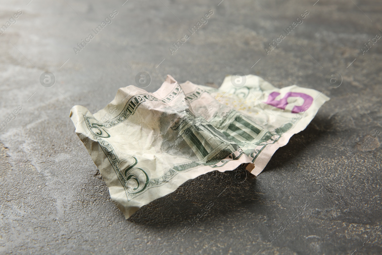 Photo of One crumpled dollar banknote on grey table, closeup