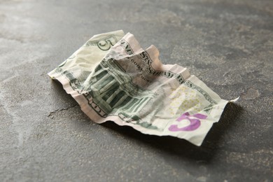 Photo of One crumpled dollar banknote on grey table, closeup