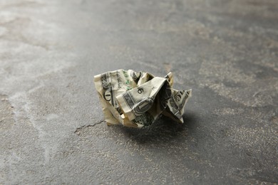 Photo of One crumpled dollar banknote on grey table, closeup