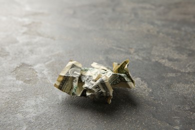 Photo of One crumpled dollar banknote on grey table, closeup