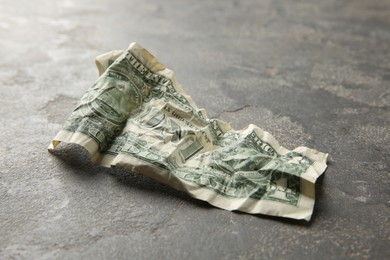 Photo of One crumpled dollar banknote on grey table, closeup