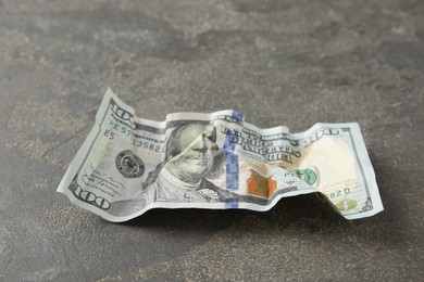 Photo of One crumpled dollar banknote on grey table, closeup