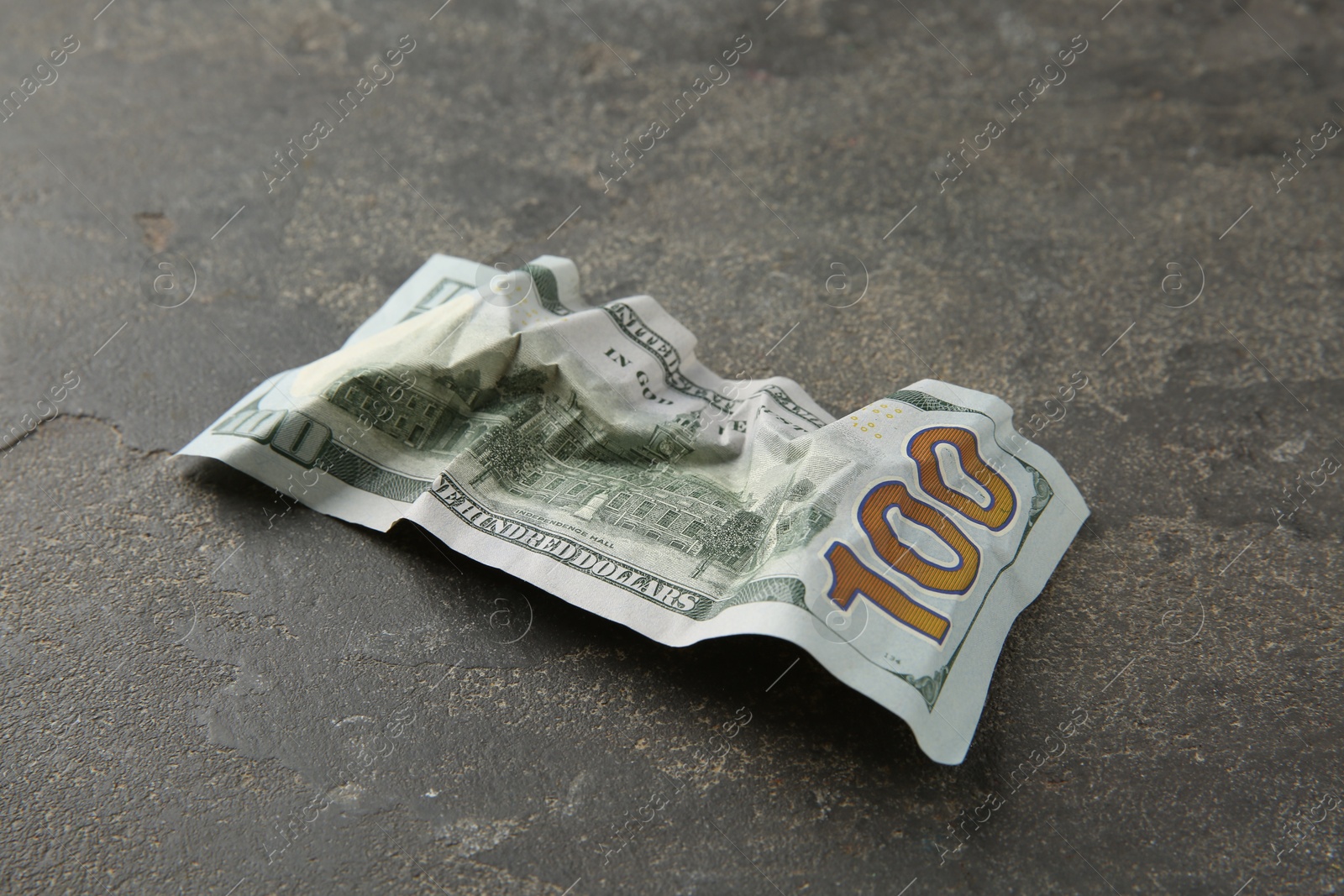 Photo of One crumpled dollar banknote on grey table, closeup