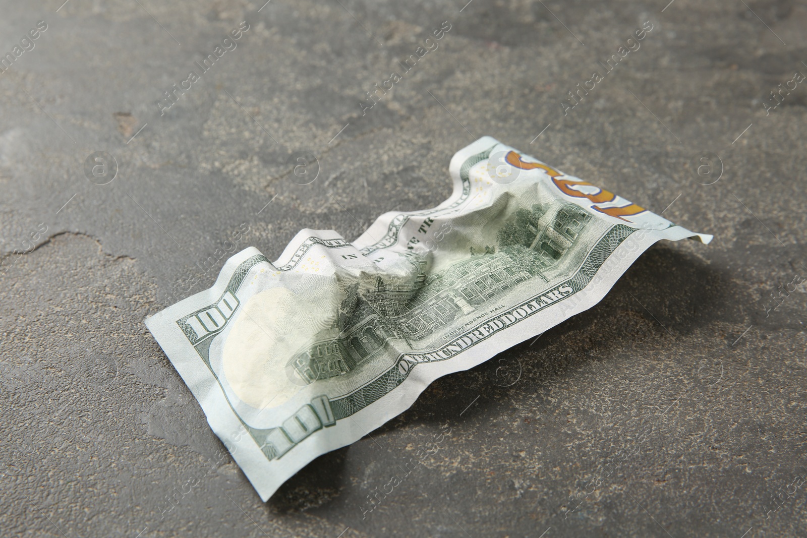 Photo of One crumpled dollar banknote on grey table, closeup