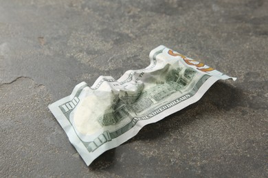 Photo of One crumpled dollar banknote on grey table, closeup