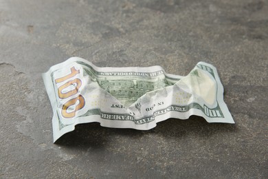 Photo of One crumpled dollar banknote on grey table, closeup