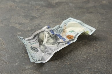 Photo of One crumpled dollar banknote on grey table, closeup