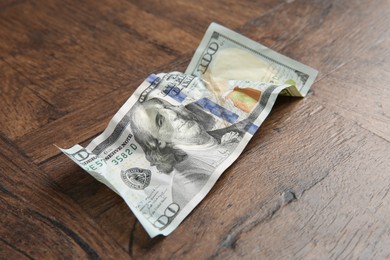 Photo of One crumpled dollar banknote on wooden table, closeup