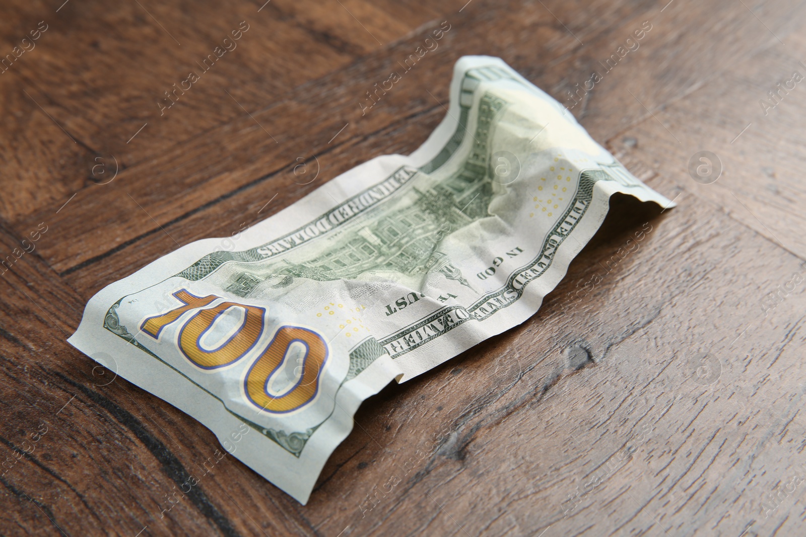 Photo of One crumpled dollar banknote on wooden table, closeup