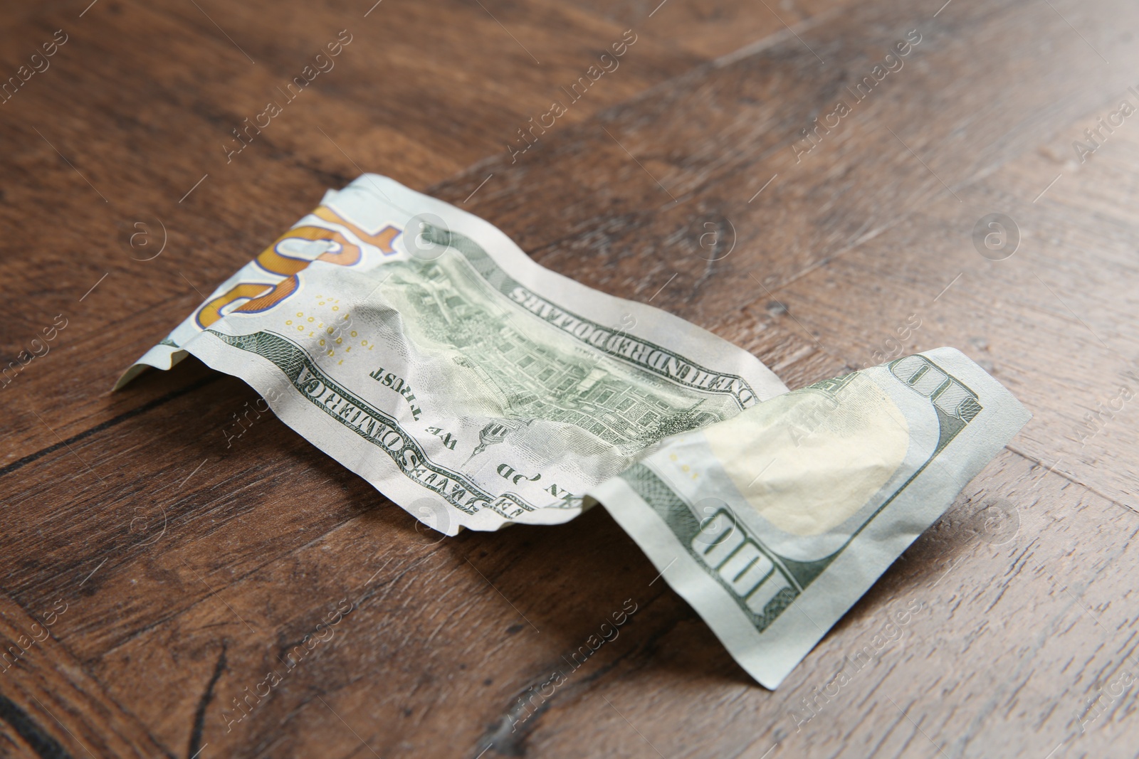 Photo of One crumpled dollar banknote on wooden table, closeup