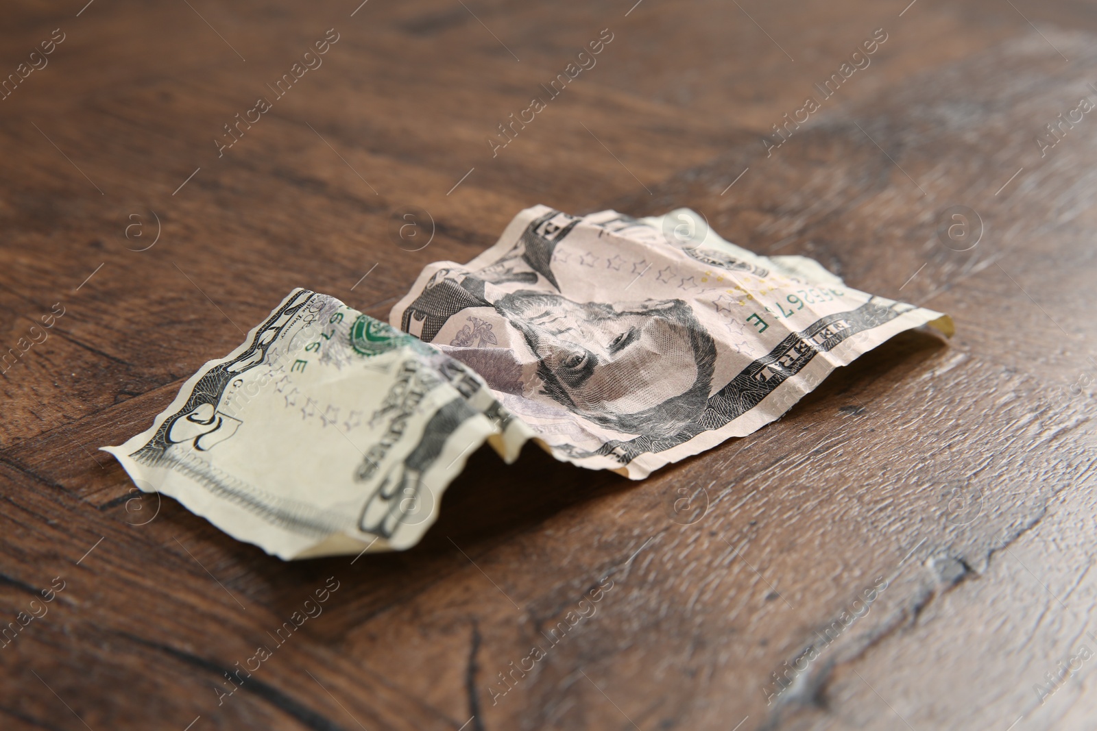 Photo of One crumpled dollar banknote on wooden table, closeup