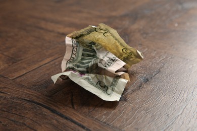 Photo of One crumpled dollar banknote on wooden table, closeup