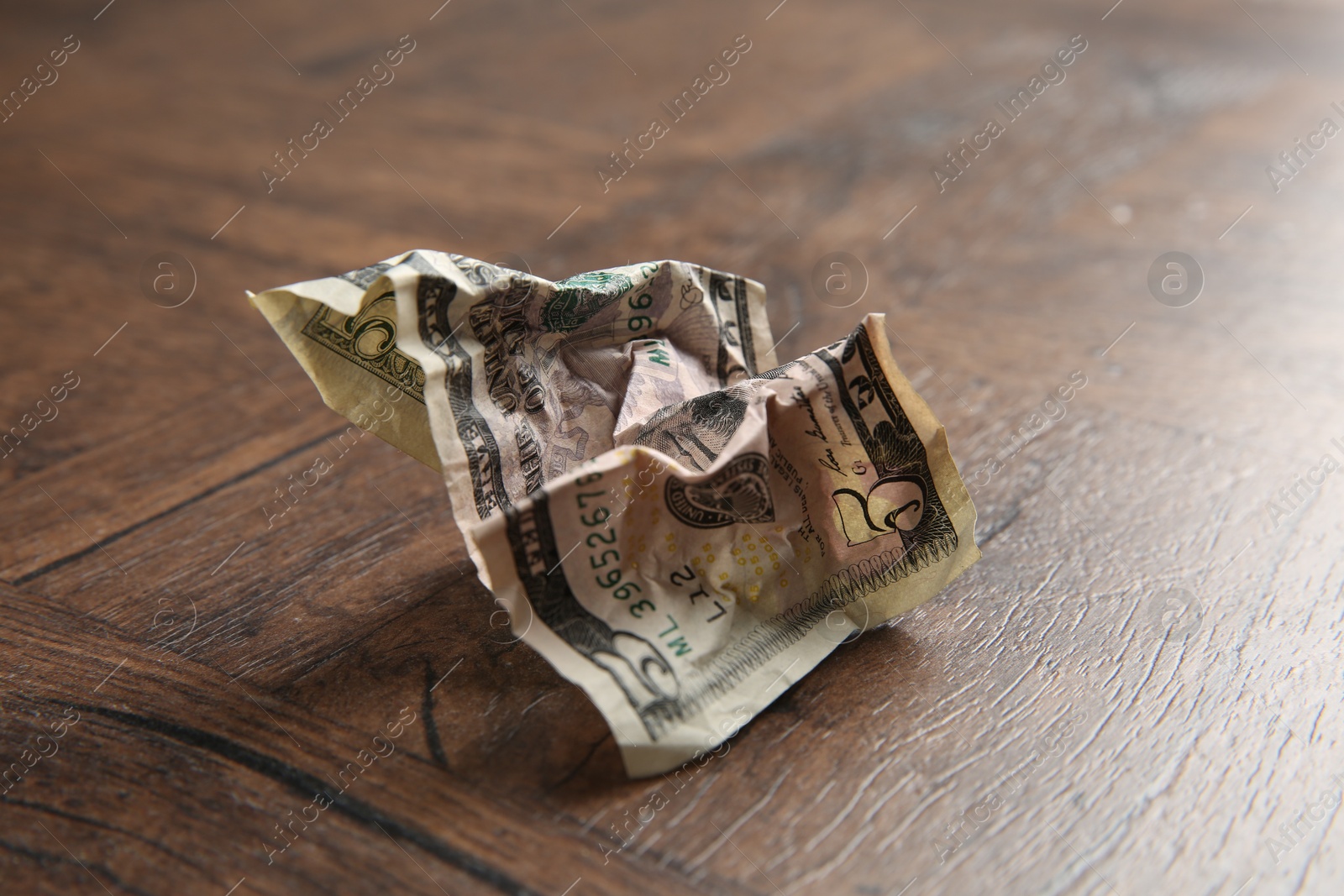 Photo of One crumpled dollar banknote on wooden table, closeup