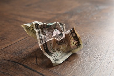 Photo of One crumpled dollar banknote on wooden table, closeup