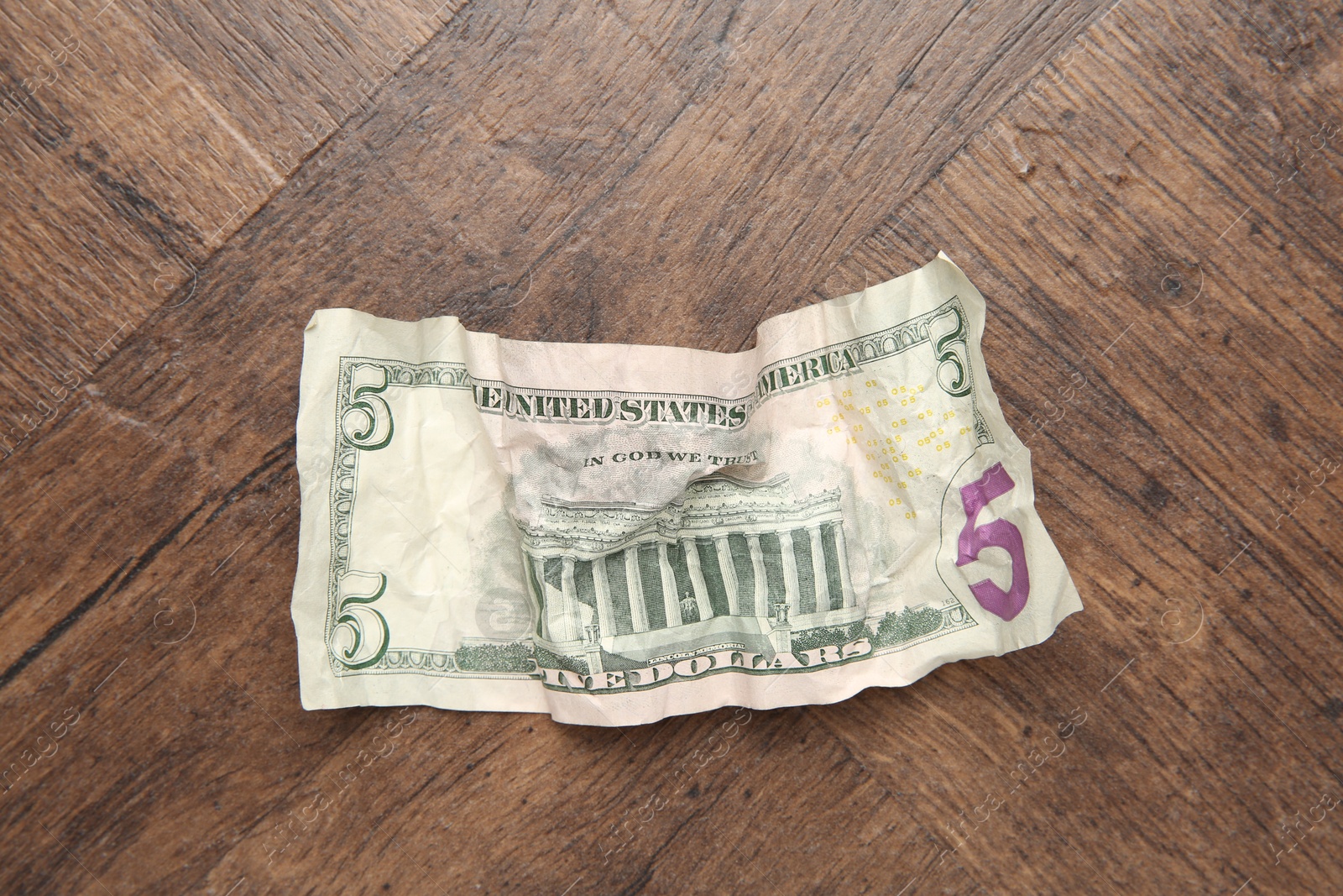 Photo of One crumpled dollar banknote on wooden table, top view