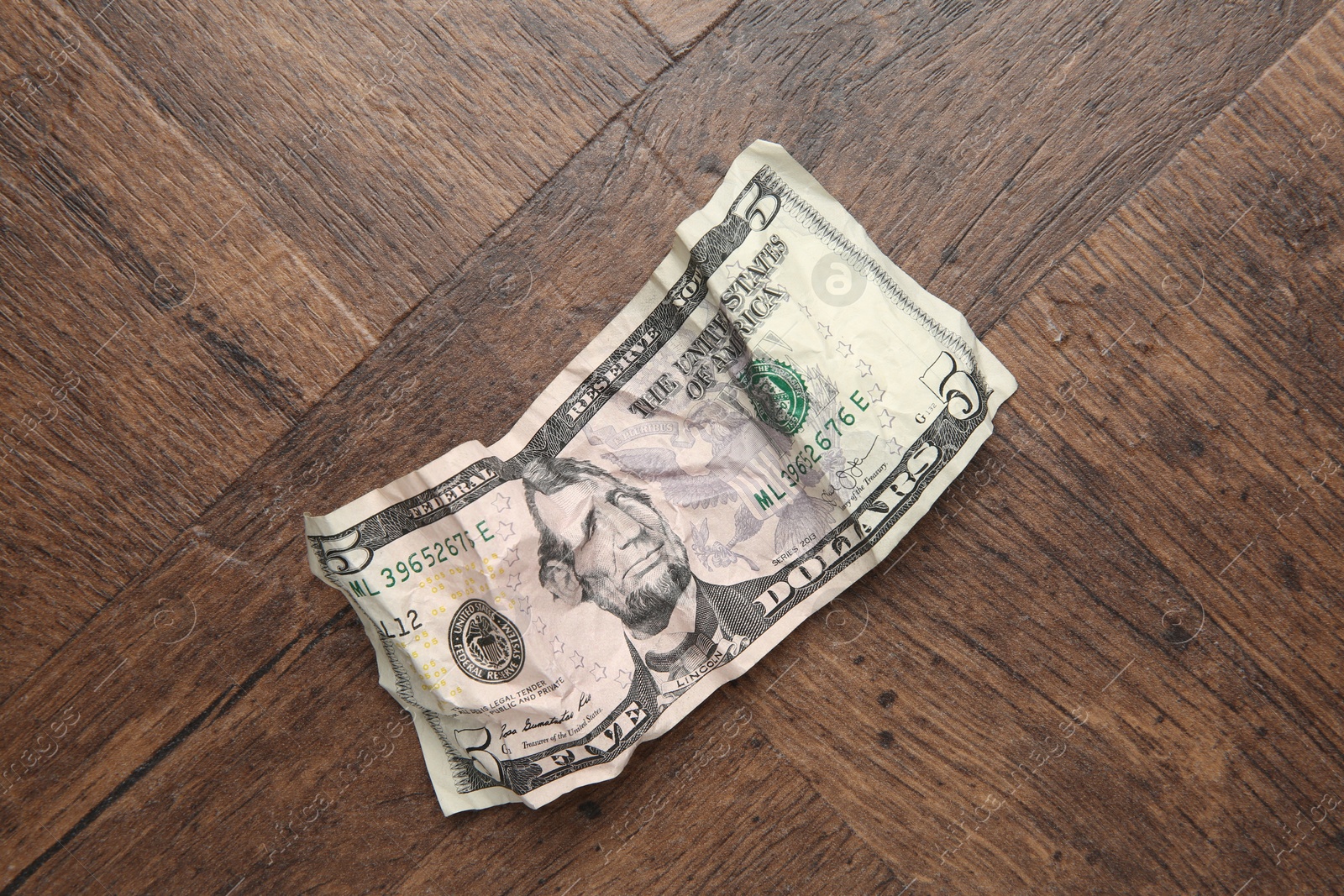 Photo of One crumpled dollar banknote on wooden table, top view