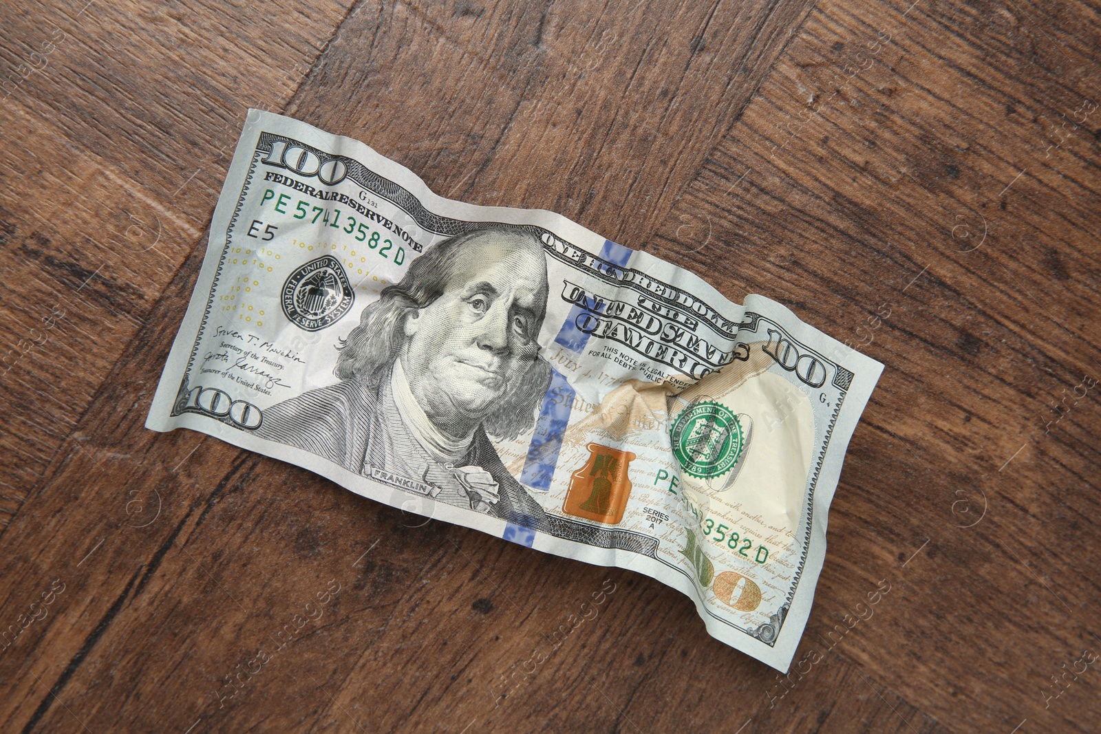 Photo of One crumpled dollar banknote on wooden table, top view