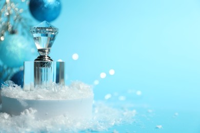 Photo of Christmas composition with perfume bottle and snow on light blue background, closeup. Space for text