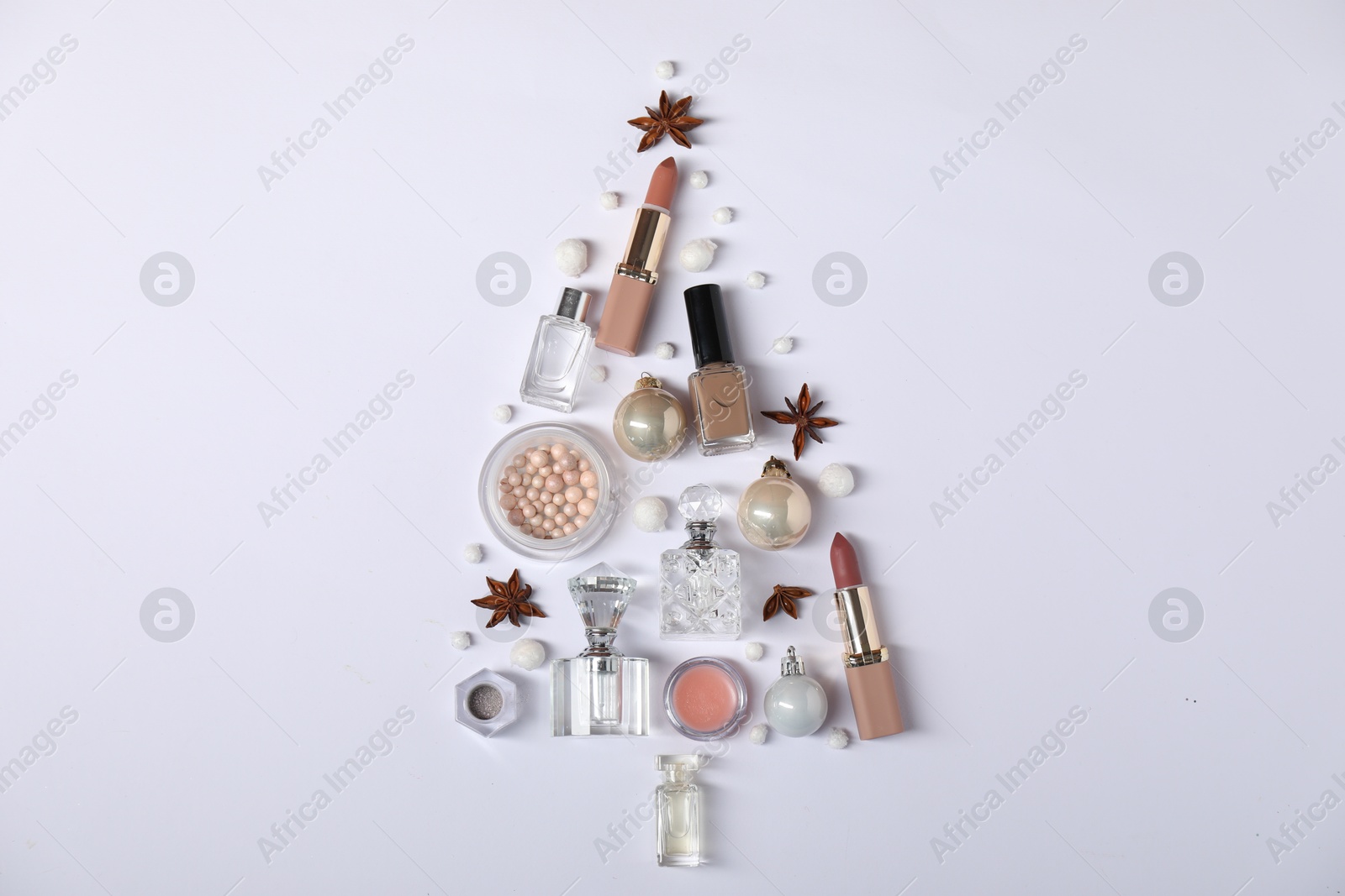 Photo of Christmas tree shape made of perfume bottles and cosmetic products on white background, flat lay