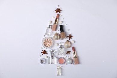 Christmas tree shape made of perfume bottles and cosmetic products on white background, flat lay