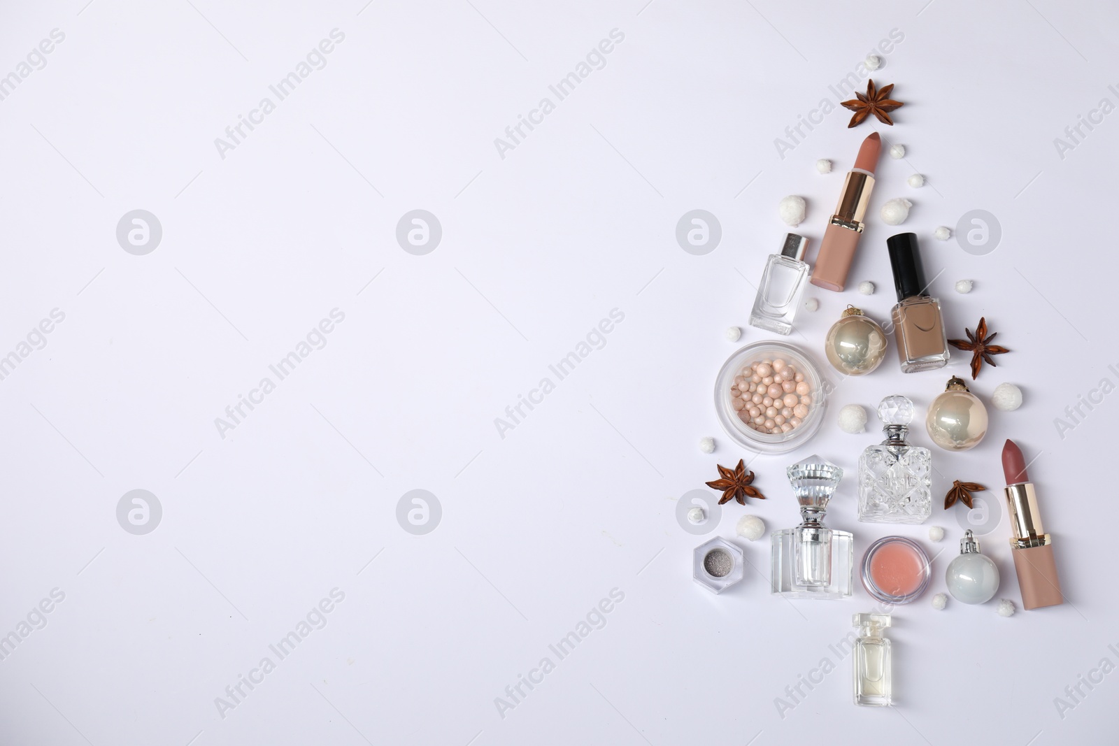 Photo of Christmas tree shape made of perfume bottles and cosmetic products on white background, flat lay. Space for text