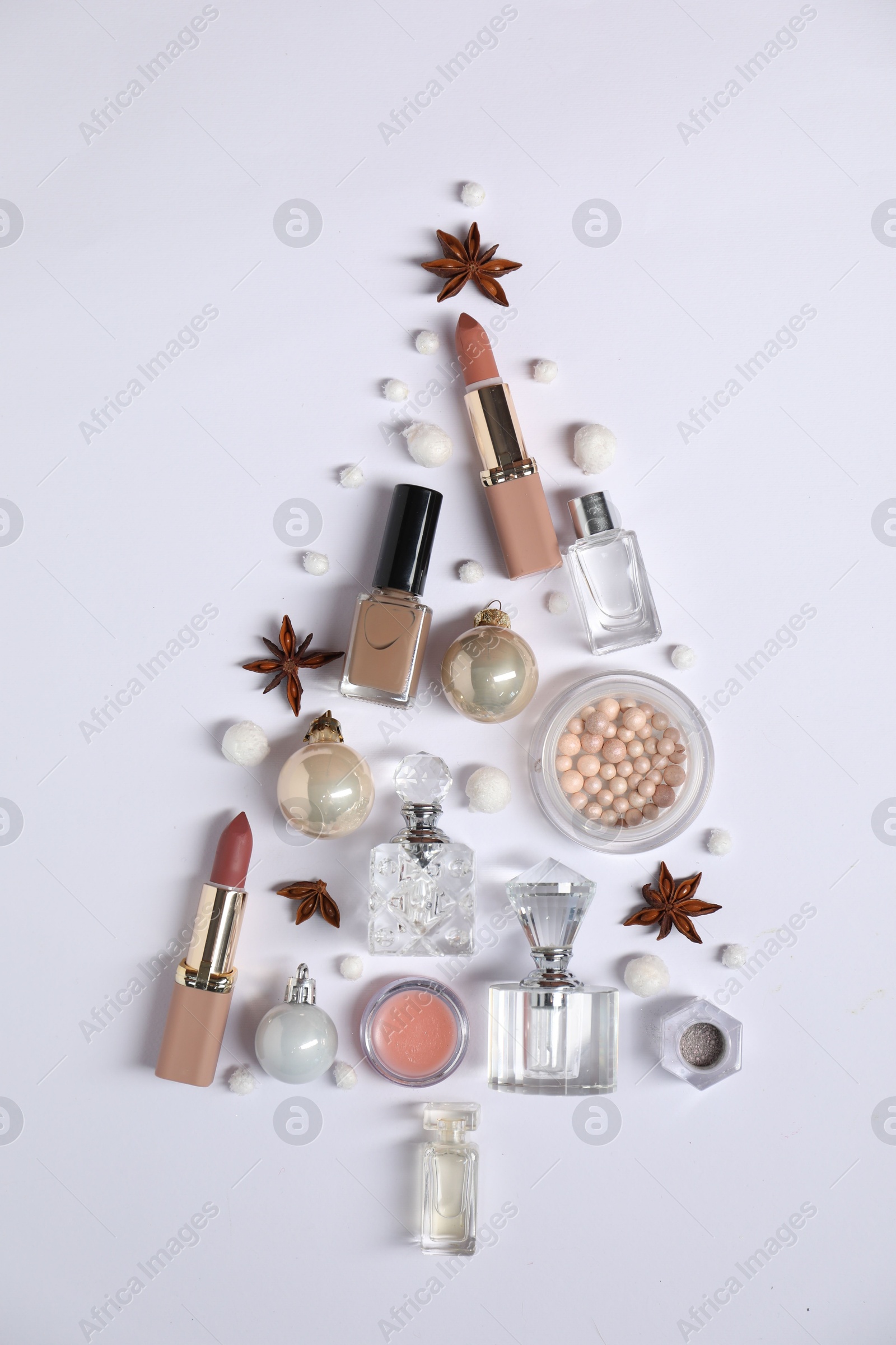 Photo of Christmas tree shape made of perfume bottles and cosmetic products on white background, flat lay