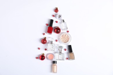 Photo of Christmas tree shape made of perfume bottles and cosmetic products on white background, flat lay