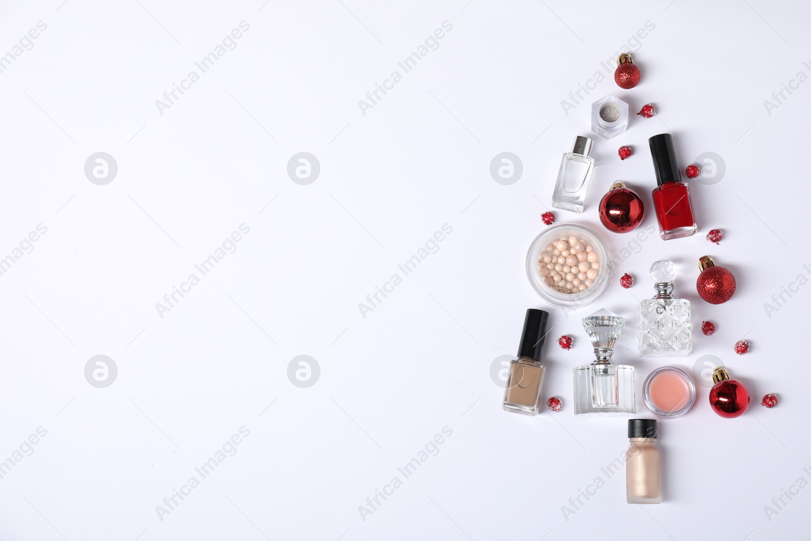 Photo of Christmas tree shape made of perfume bottles and cosmetic products on white background, flat lay. Space for text