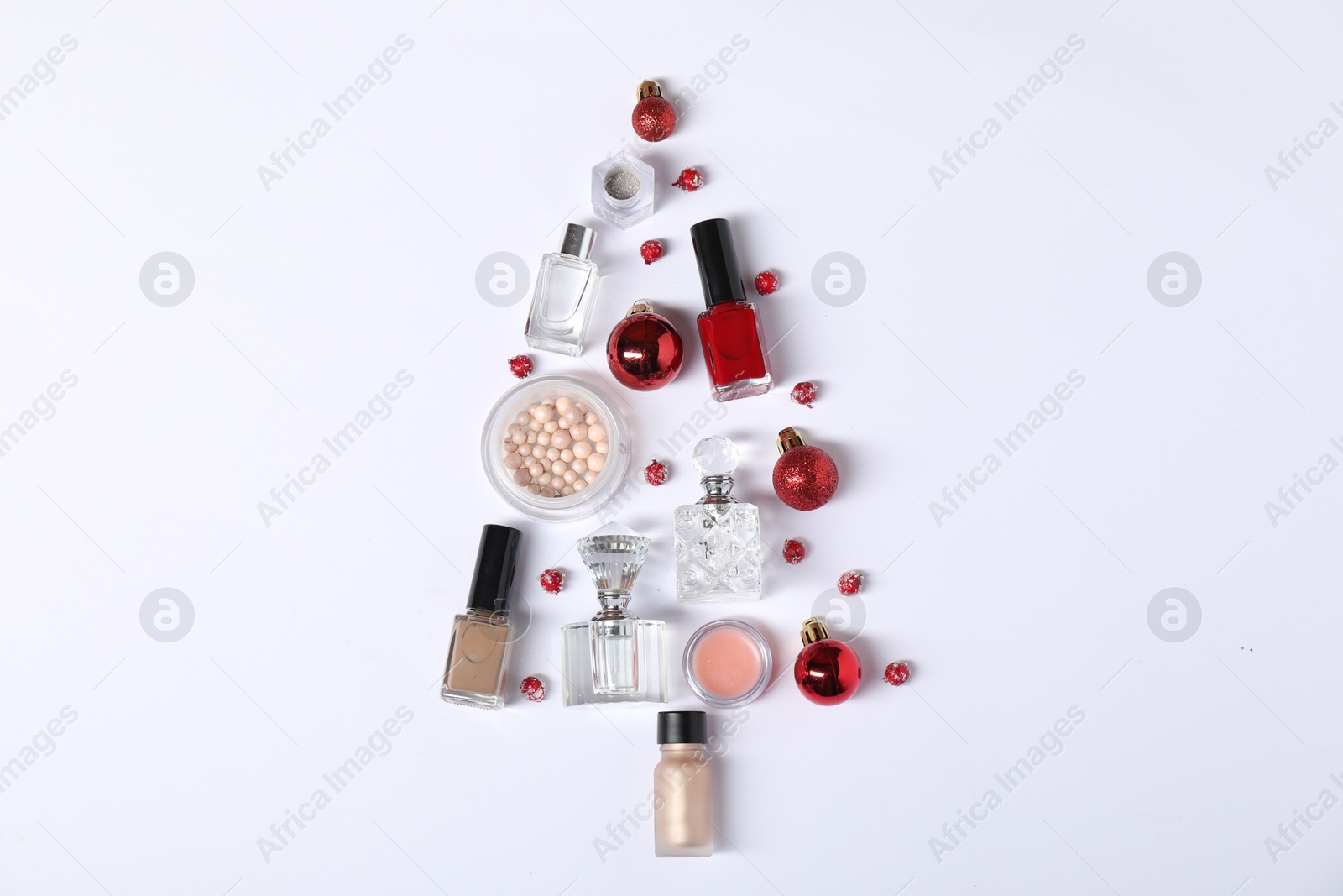 Photo of Christmas tree shape made of perfume bottles and cosmetic products on white background, flat lay