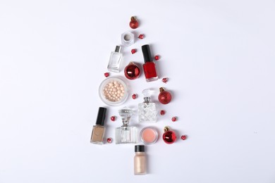 Christmas tree shape made of perfume bottles and cosmetic products on white background, flat lay