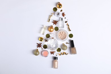 Photo of Christmas tree shape made of perfume bottles and cosmetic products on white background, flat lay