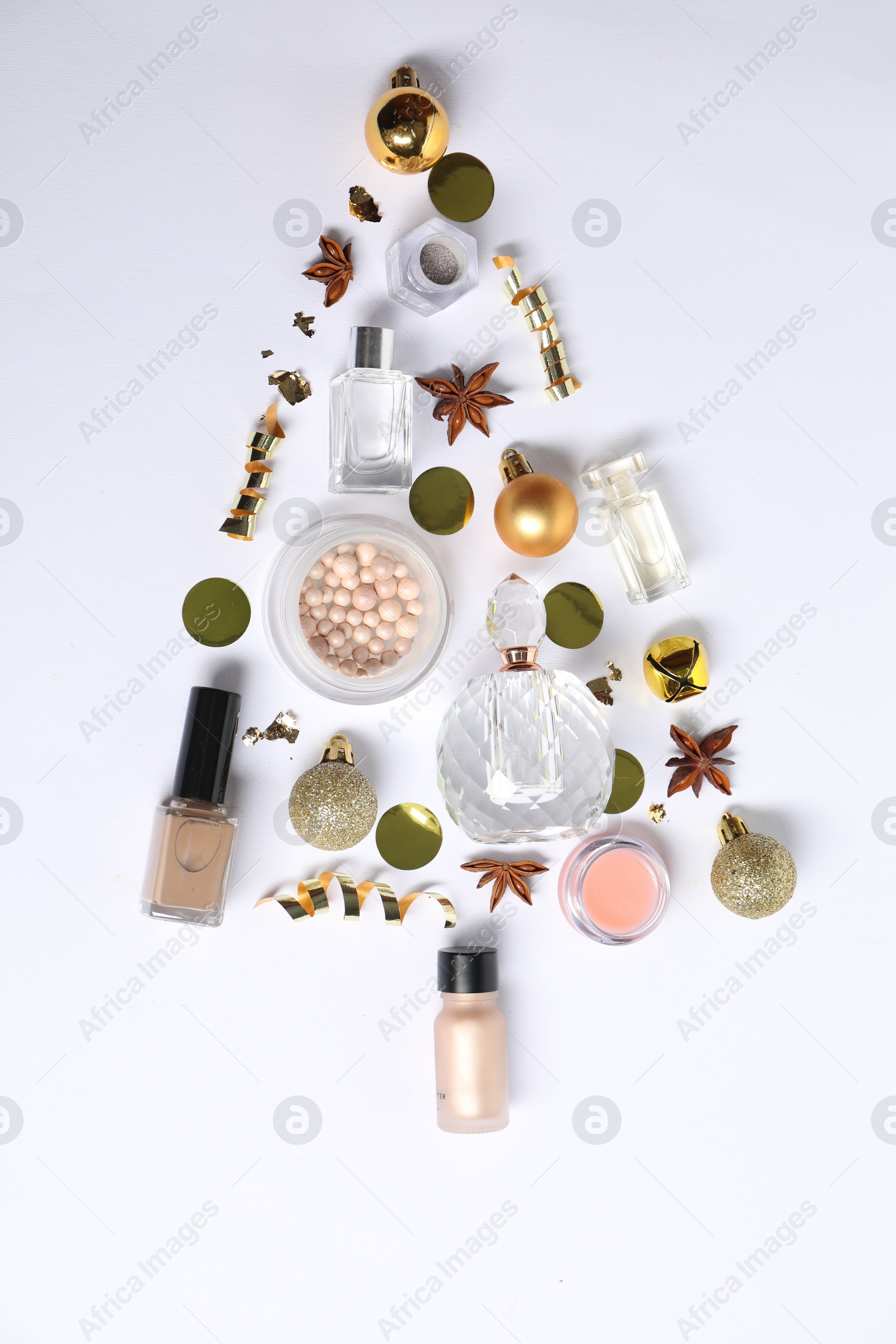 Photo of Christmas tree shape made of perfume bottles and cosmetic products on white background, flat lay