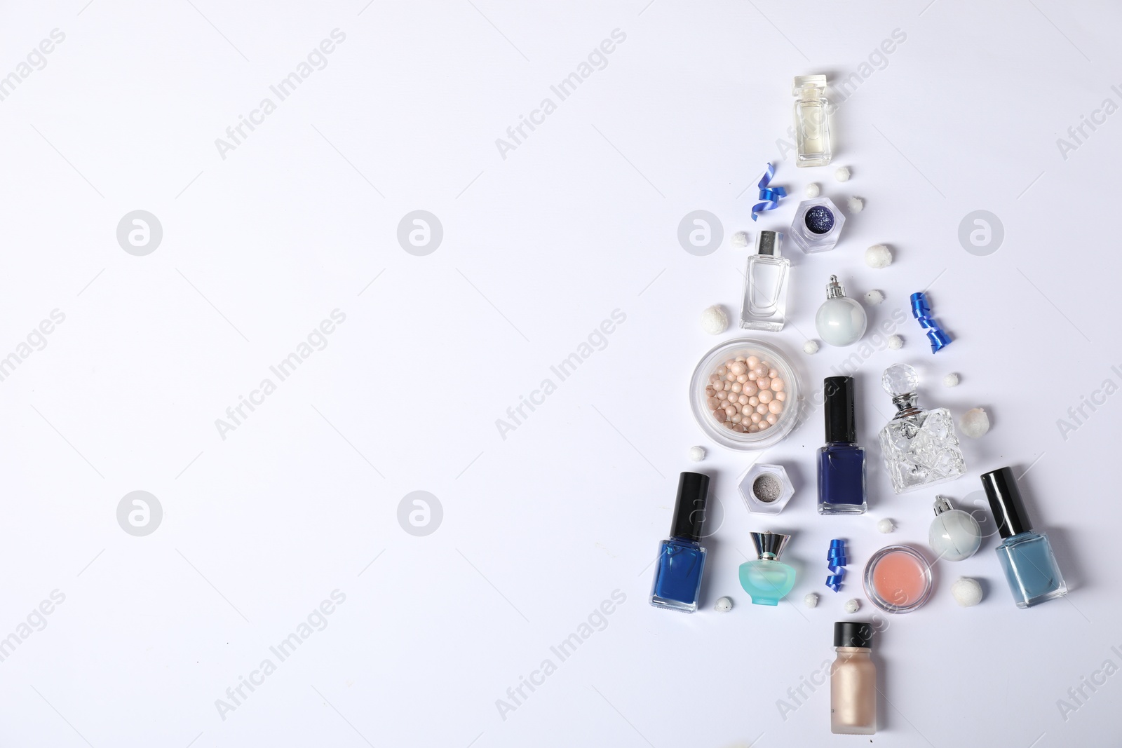 Photo of Christmas tree shape made of perfume bottles and cosmetic products on white background, flat lay. Space for text