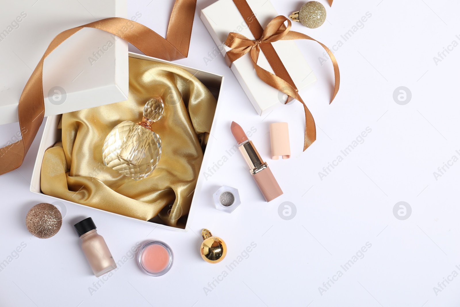 Photo of Christmas composition with perfume bottle and cosmetic products on white background, flat lay. Space for text