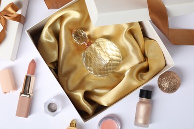 Photo of Christmas composition with perfume bottle and cosmetic products on white background, flat lay