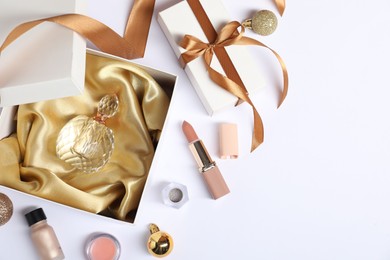 Photo of Christmas composition with perfume bottle and cosmetic products on white background, flat lay. Space for text