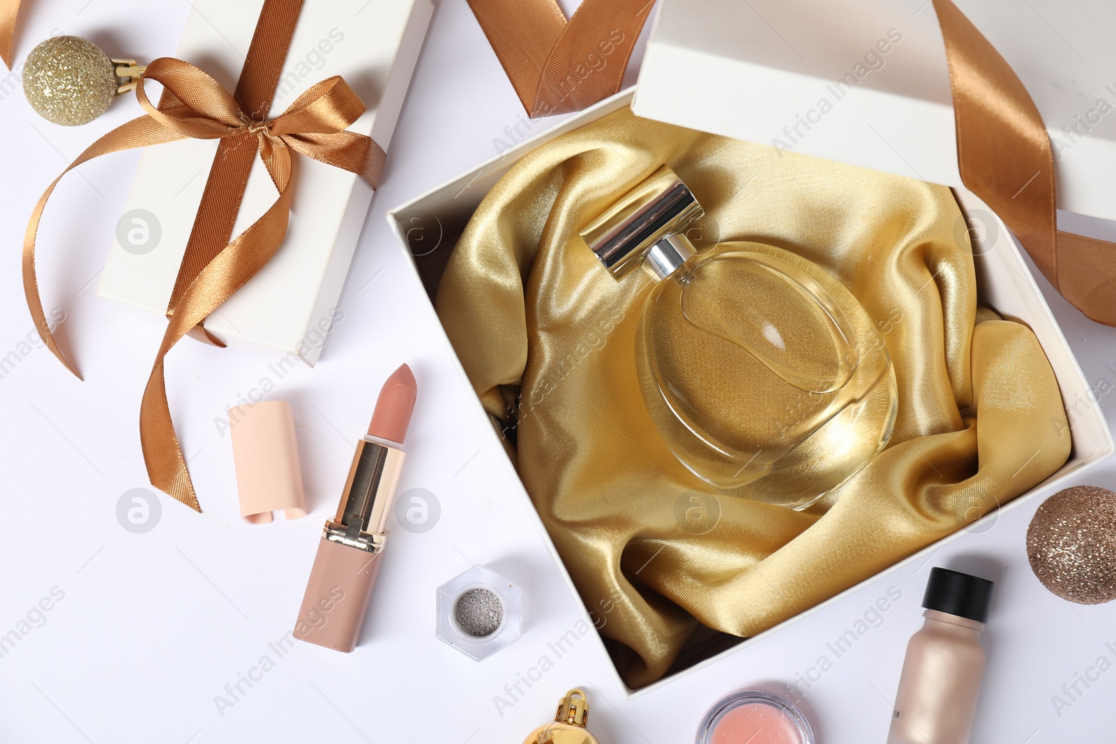 Photo of Christmas composition with perfume bottle and cosmetic products on white background, flat lay