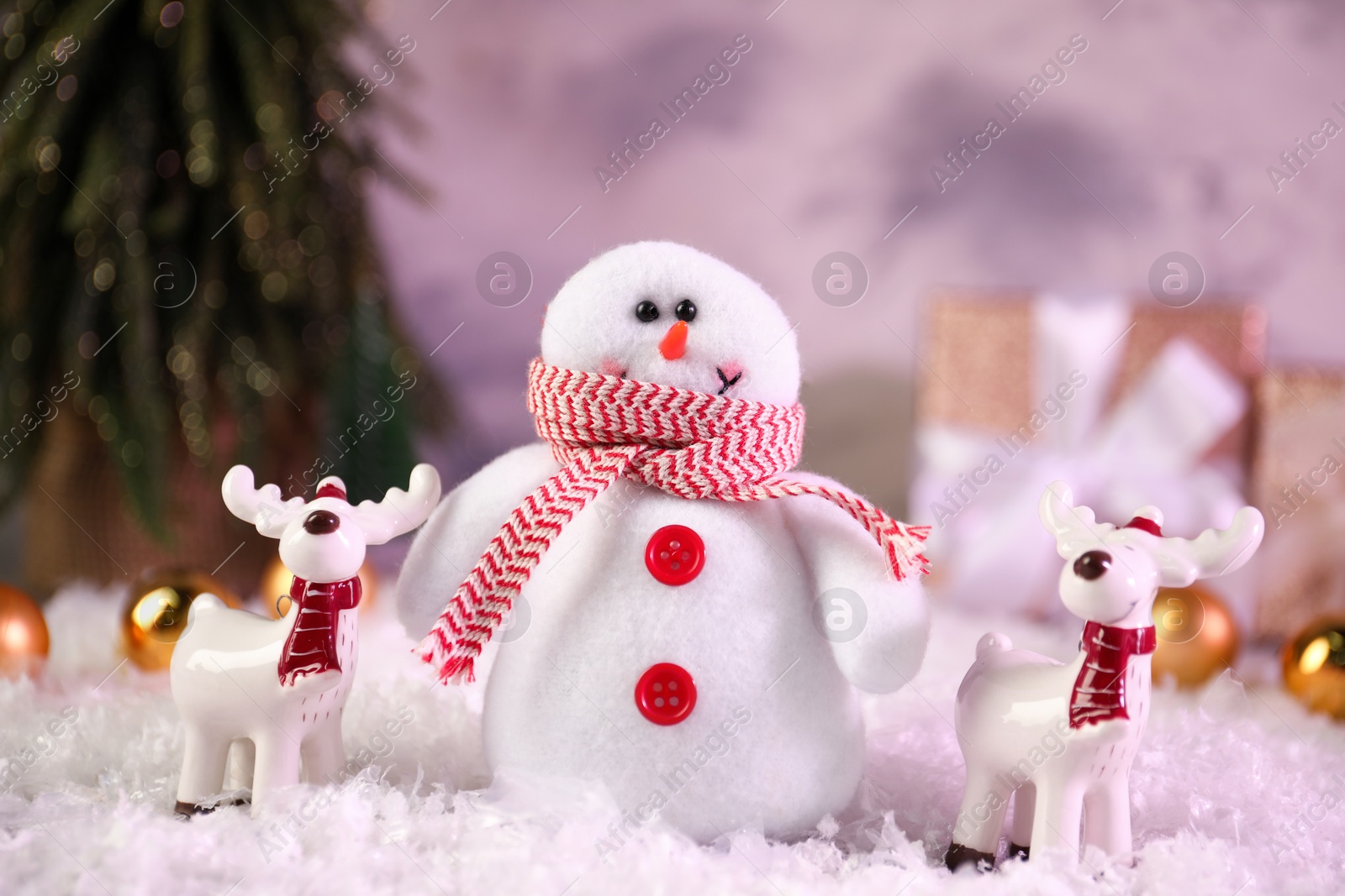 Photo of Funny snowman figure and deers on artificial snow, closeup