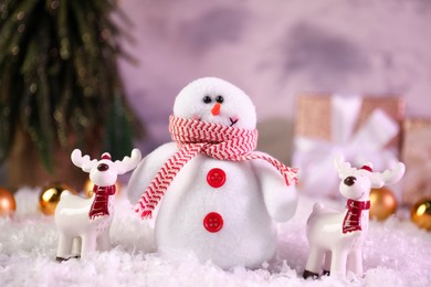 Photo of Funny snowman figure and deers on artificial snow, closeup