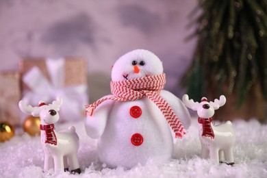 Photo of Funny snowman figure and deers on artificial snow, closeup