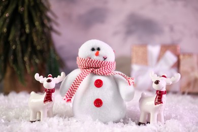 Photo of Funny snowman figure and deers on artificial snow, closeup