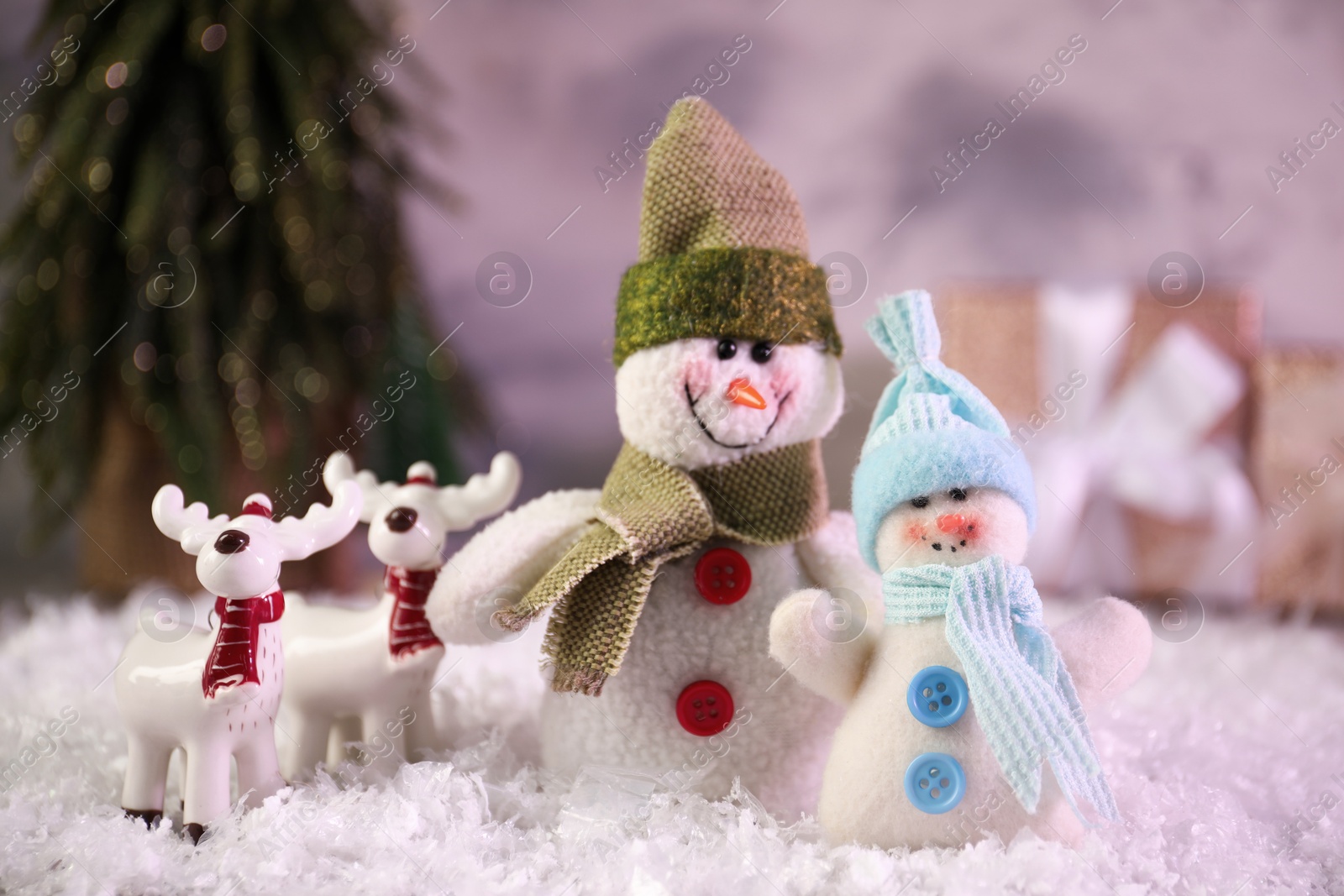 Photo of Funny snowmen figures and deers on artificial snow, closeup