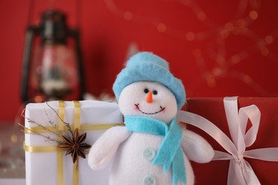 Photo of Funny snowman figure and Christmas gifts on table, closeup