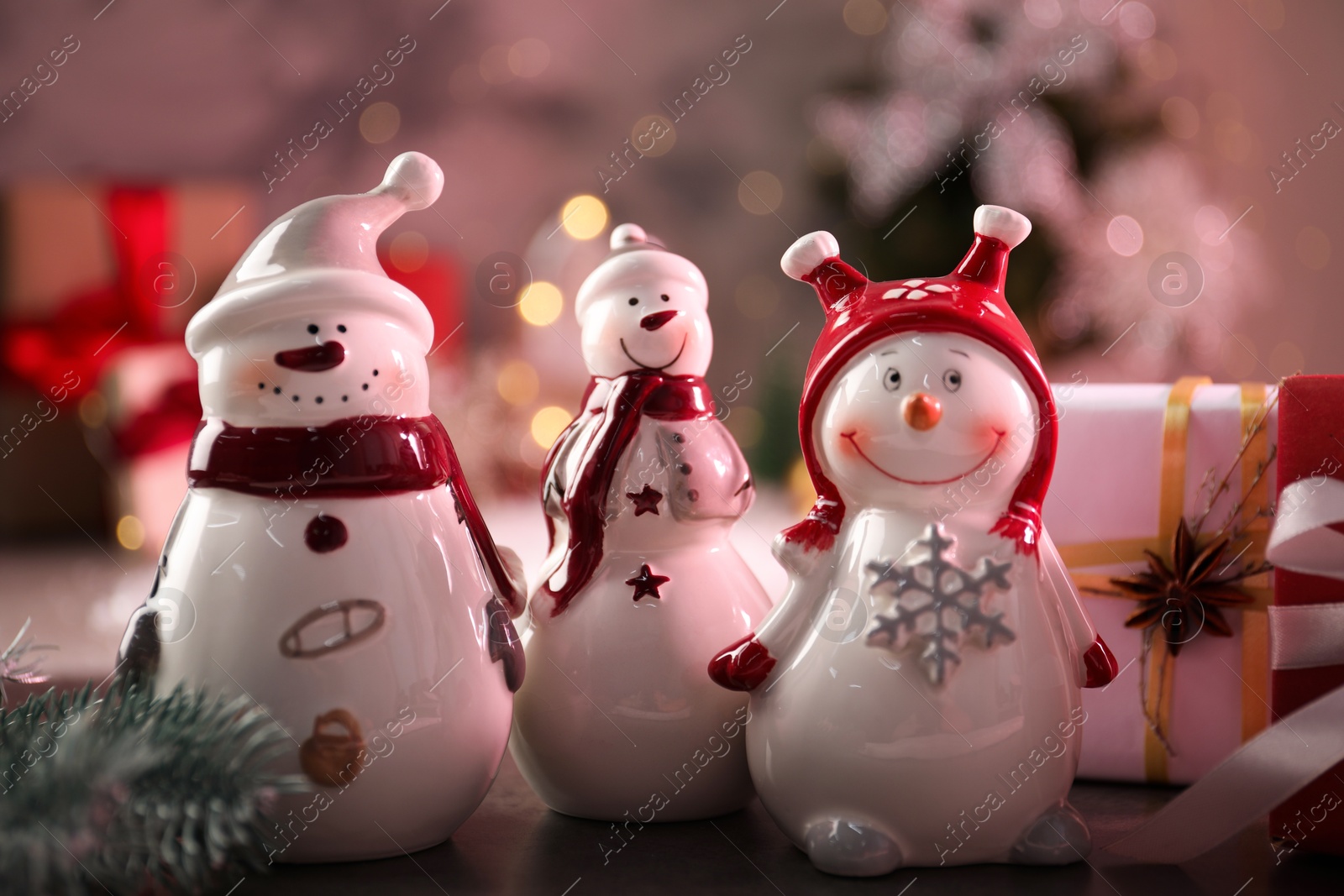 Photo of Funny snowmen figures and Christmas decor on table, closeup