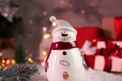 Photo of Funny snowman figure and fir branch on artificial snow, closeup