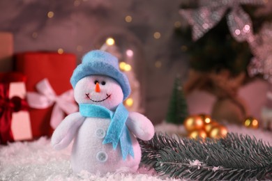 Photo of Funny snowman figure and fir branch on artificial snow